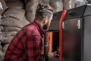 A man in a room with a solid fuel boiler, working on biofuel, economical heating.